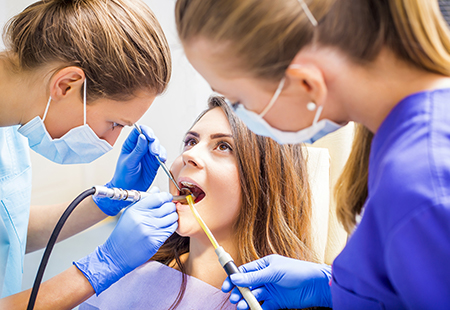 The image shows dental professionals performing a procedure on a patient s mouth using specialized equipment.
