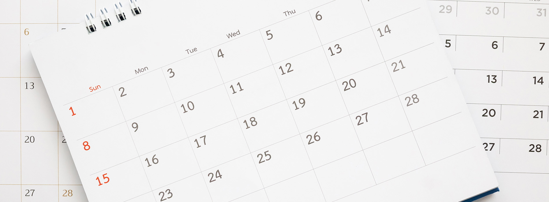 The image shows a calendar with dates visible, placed on top of another calendar with the same dates, against a blurred background.