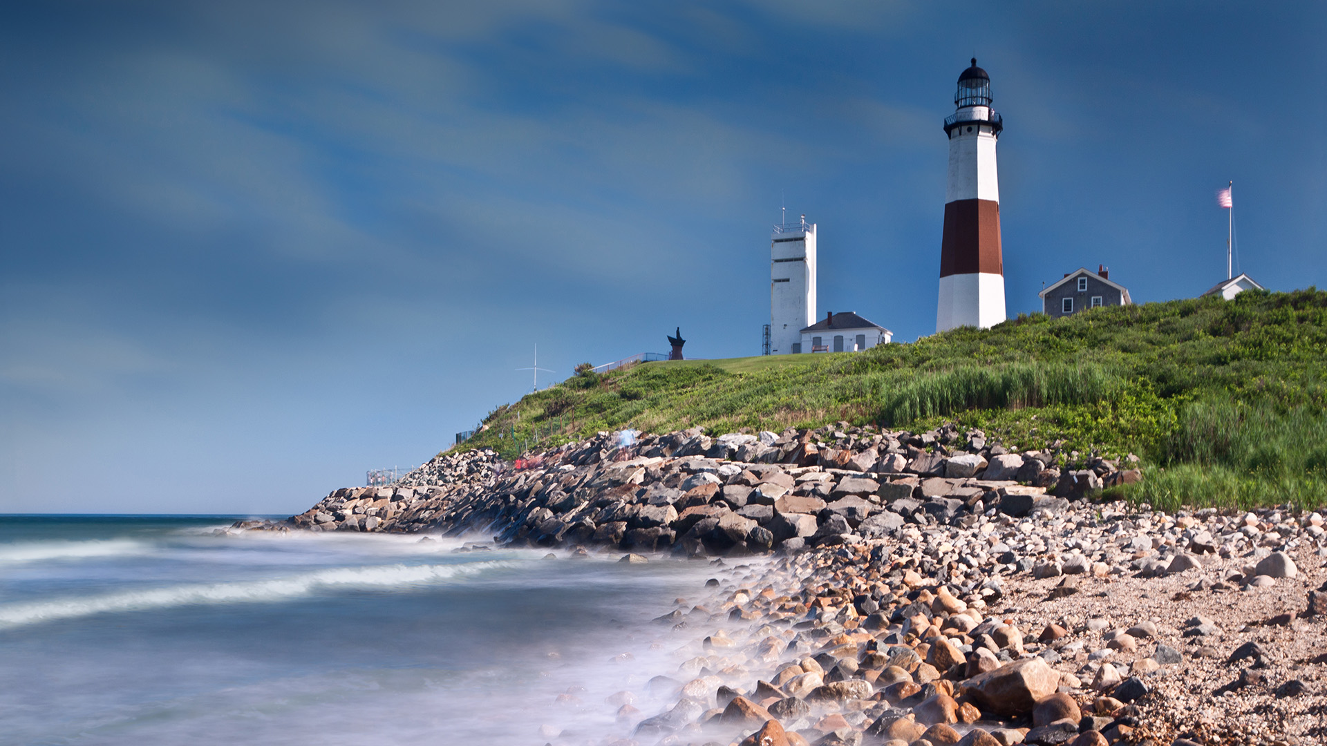 A scenic coastal view with a lighthouse on a rocky shoreline.