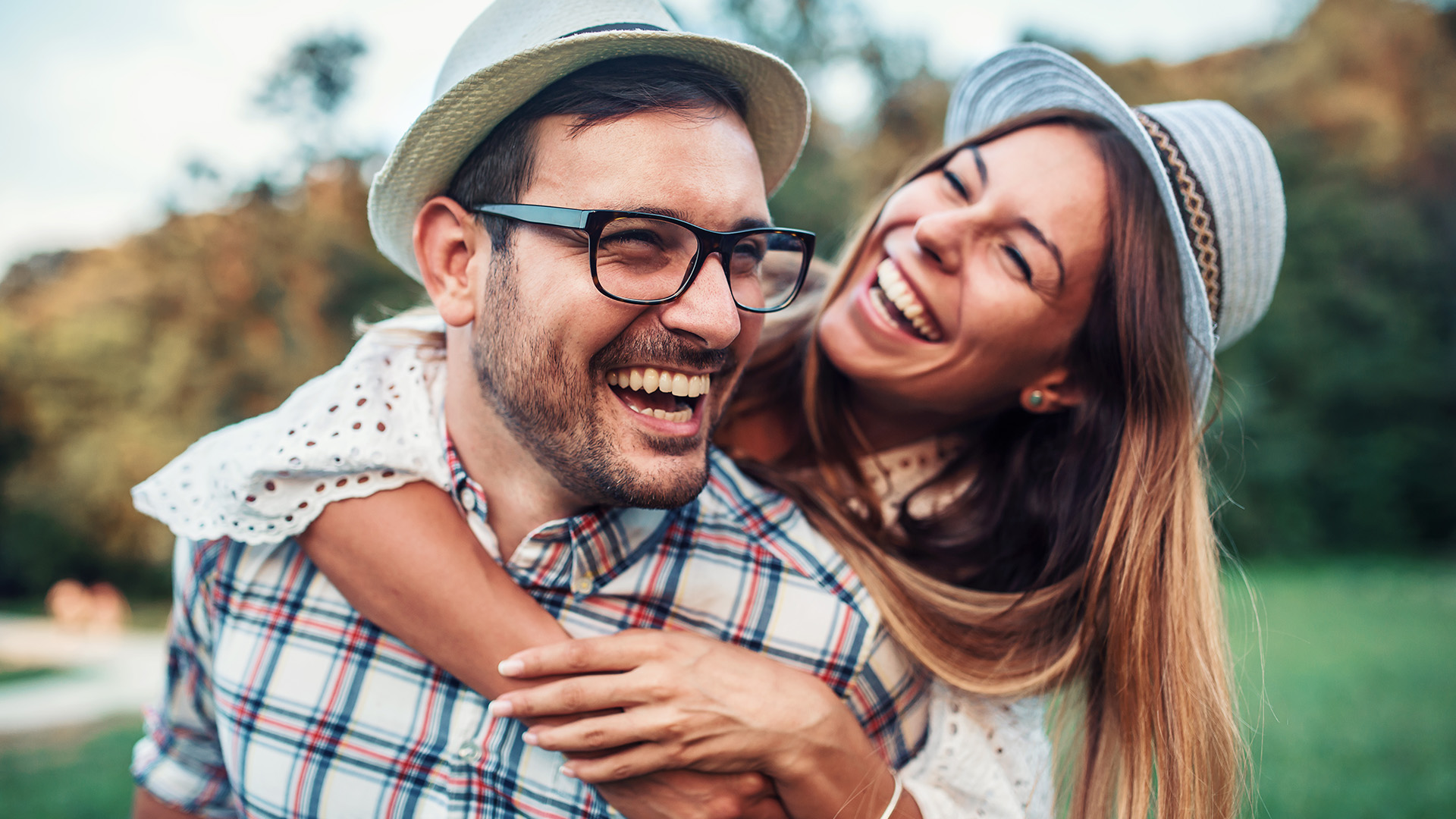 The image shows a man and woman embracing each other outdoors with smiles on their faces  they appear to be enjoying a moment together.