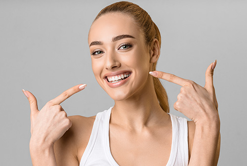 A woman with her eyes closed, pointing upwards, with a smile on her face, showcasing a product.