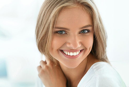The image features a woman with blonde hair smiling at the camera against a blurred background.