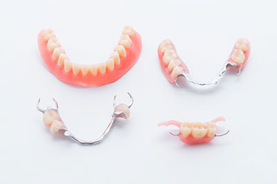 This image shows a set of dentures with a toothy grin, displayed on a white background alongside a single tooth-shaped object, all presented in a collage format.