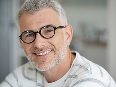 A man with glasses smiling at the camera.